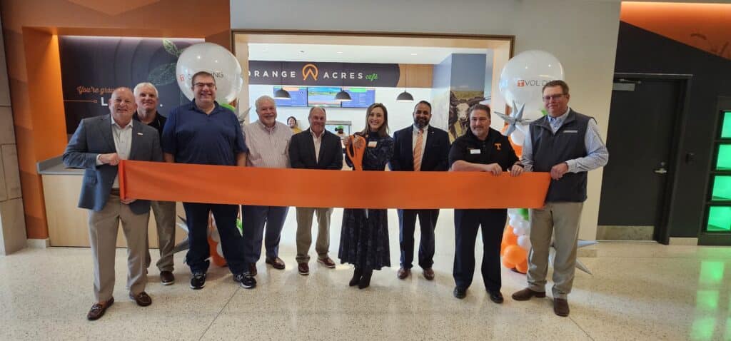 UT senior leadership post for a ribbon cutting picture in front of Orange Acres Cafè.